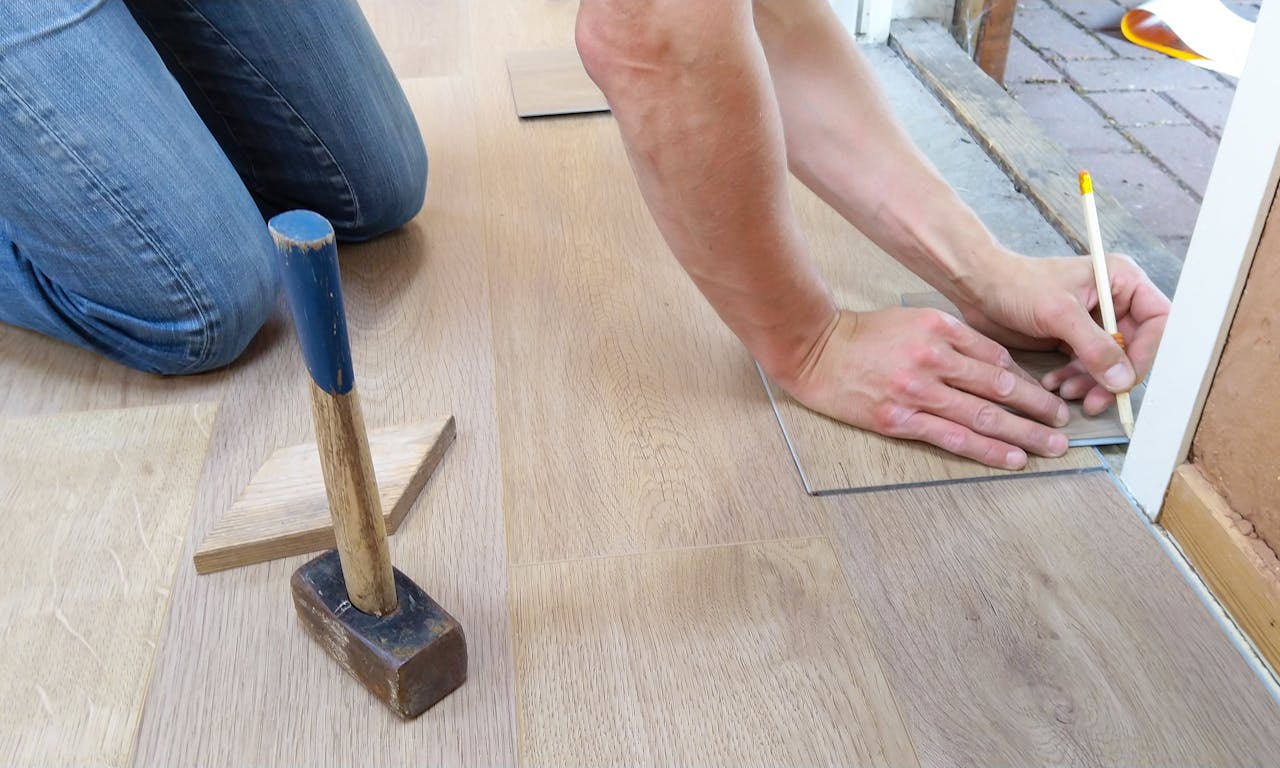 services-04 A craftsman carefully measures and marks wooden floor panels for precise installation.